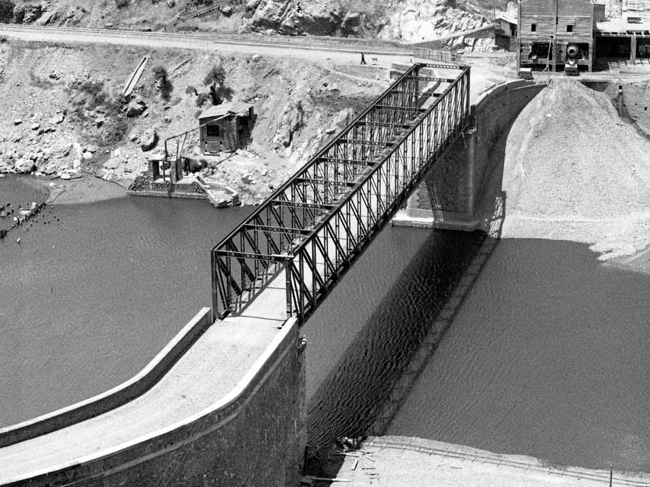Fotografía blanco y negro de puente metálico sobre rio